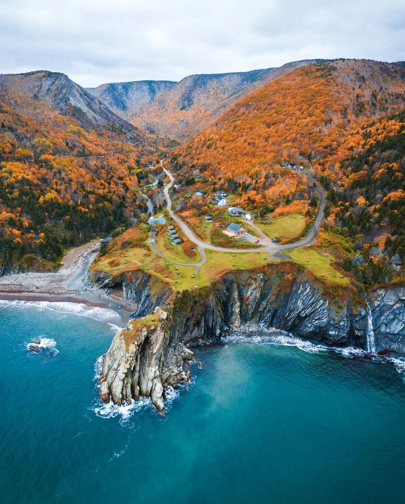 Bờ biển Nova Scotia nhìn từ trên cao với vách đá, nước xanh và rừng cây đổi màu mùa thu